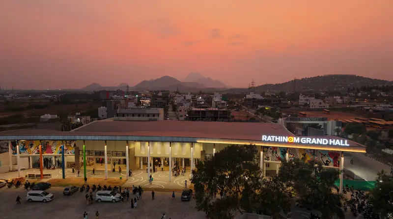 Rathinam Grand Hall illuminated at sunset with students gathered outside