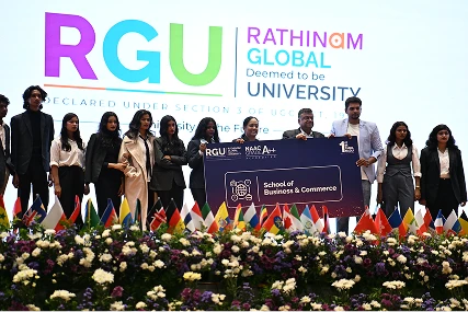 Students on stage at a Rathinam Global University event holding a School of Business and Commerce placard